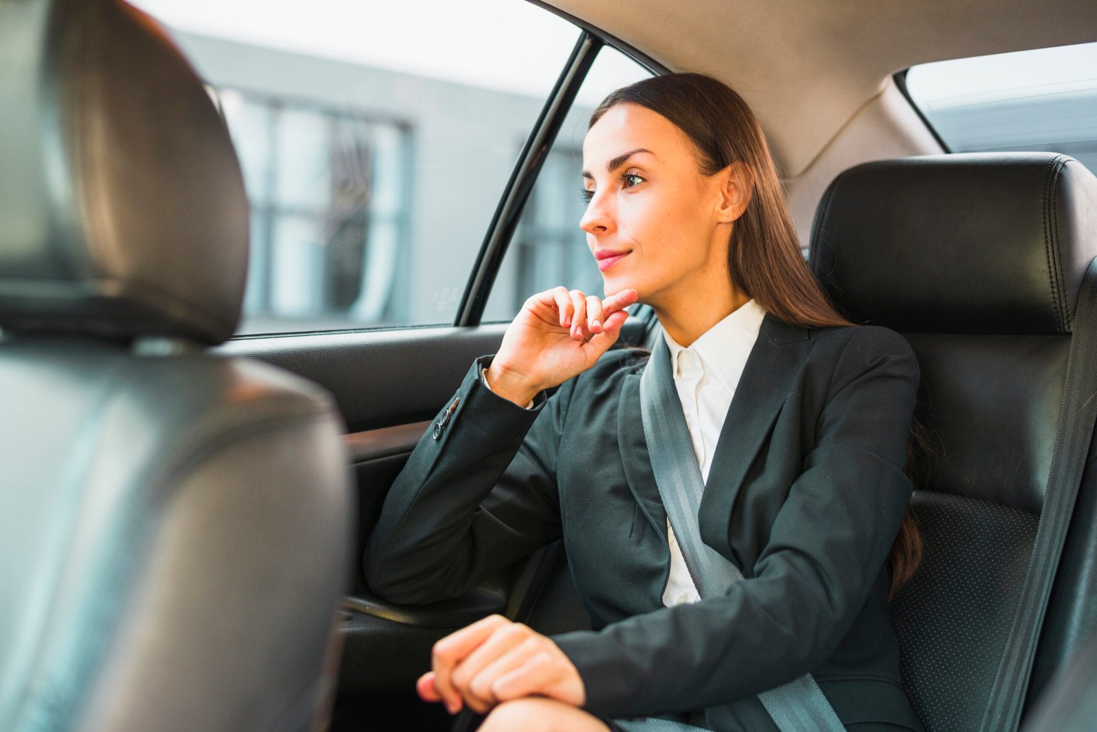 businesswoman-looking-through-window-while-traveling-by-car